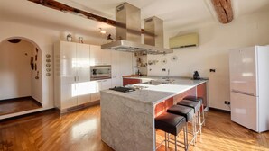 A modern kitchen with a central island, bar stools, built-in oven, and a refrigerator. - Amazing apartment in Genova with WiFi (Genova)