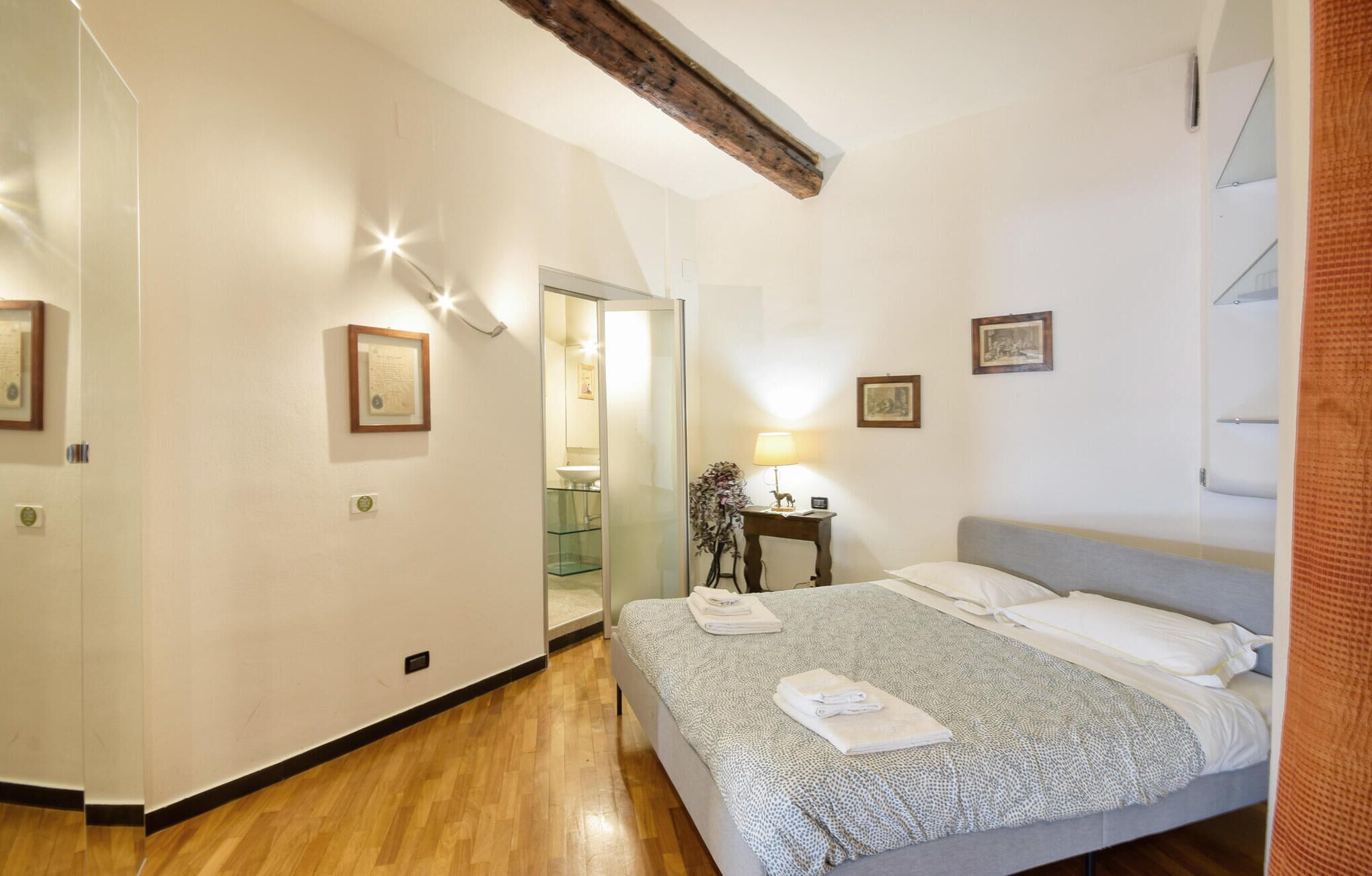 Une chambre d’hôtel avec un lit, une table de chevet, une lampe et un miroir.