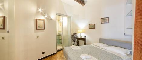 Une chambre d’hôtel avec un lit, une table de chevet, une lampe et un miroir.
