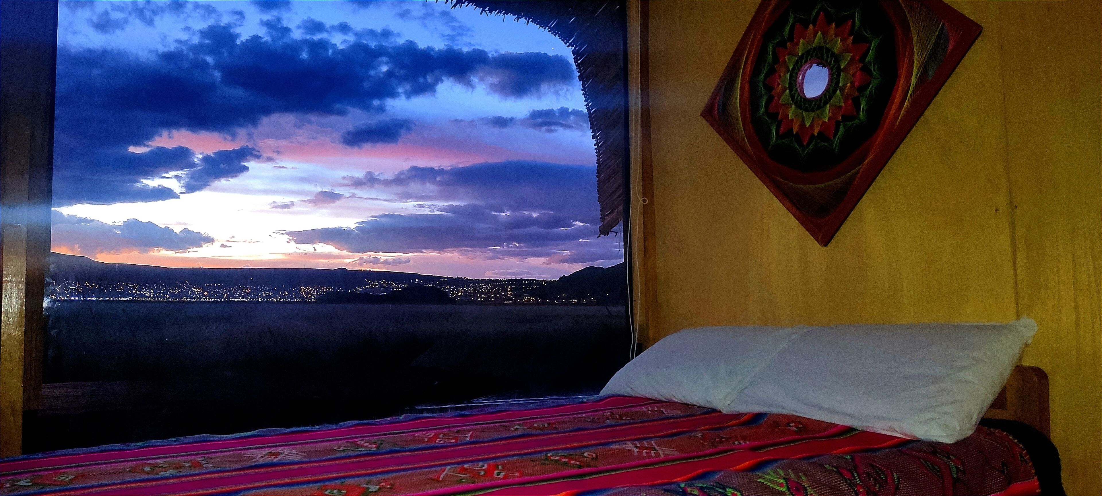 Un lit avec une couverture colorée, une tête de lit en bois et une décoration murale.