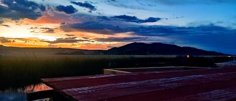 A sunset view with a wooden deck and a body of water.