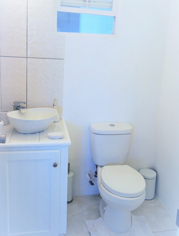 A bathroom with a white sink, toilet, and cabinet.