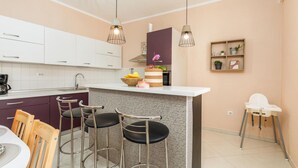Une cuisine moderne avec des meubles blancs, un plan de travail en marbre et un coin bar équipé de tabourets.