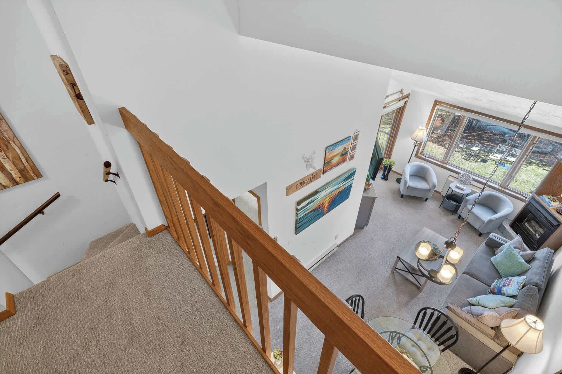Un vaste espace de vie comprenant un escalier, une cheminée et une grande fenêtre donnant sur l’extérieur.