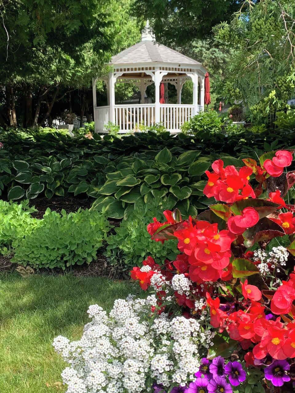 Ein Pavillon, umgeben von üppigem Grün und einer Vielzahl bunter Blumen.