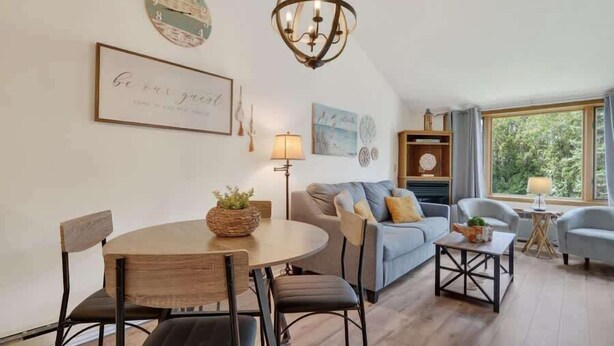 A cozy living room with a round dining table, a sofa, and a chandelier. - Ephraim’s Pearl (Unit 203) | Balcony Views, Walk to Waterfront and Downtown Charm (Ephraim)