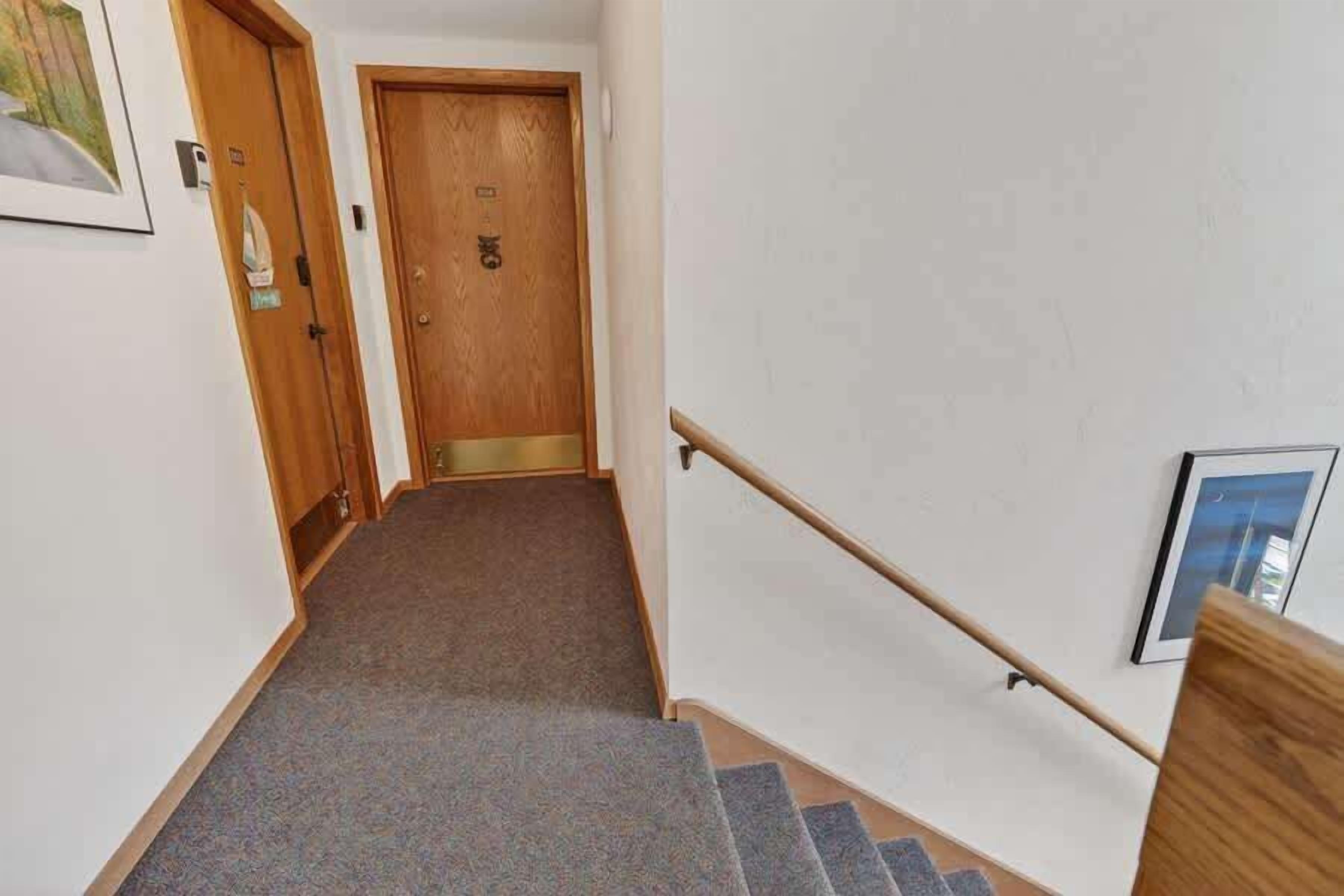 Eine Teppichstufen Treppe mit einem Holzhandlauf und einer Tür mit einem 'OK'-Hinweis.