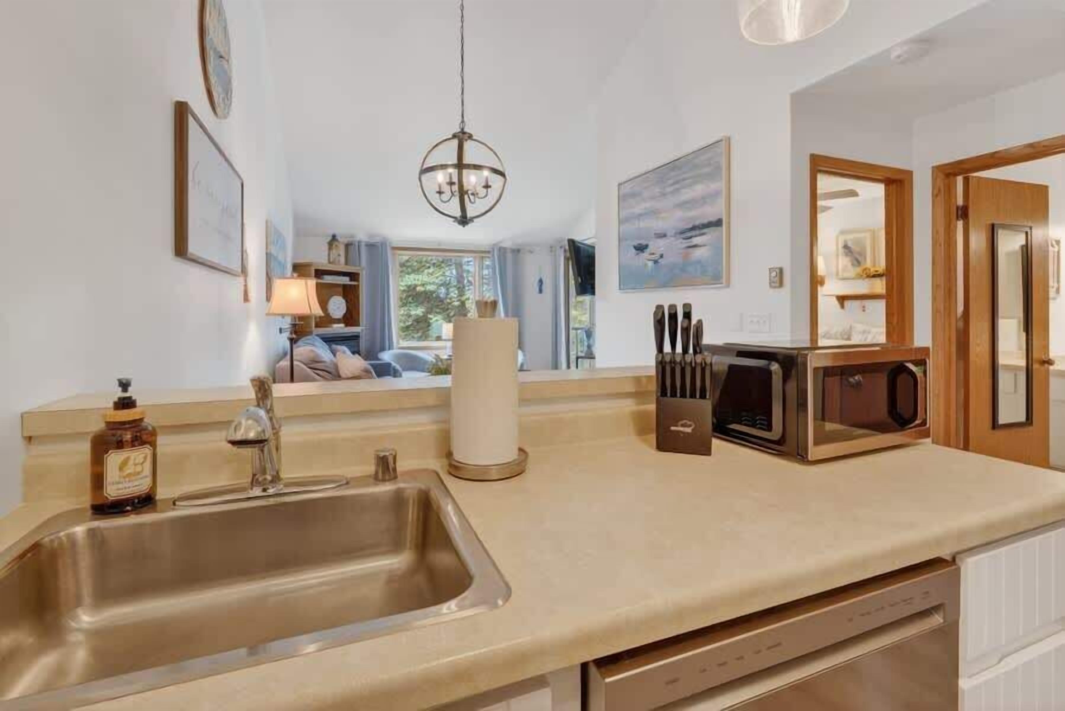 A kitchen with a stainless steel sink, a microwave, and a knife block.
