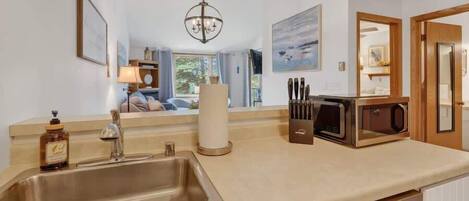 A kitchen with a stainless steel sink, a microwave, and a knife block.