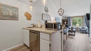 A kitchen with a microwave, a dishwasher, and a dining area with a table and chairs. - Ephraim’s Pearl (Unit 203) | Balcony Views, Walk to Waterfront and Downtown Charm (Ephraim)
