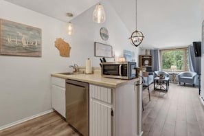 A kitchen with a microwave, a dishwasher, and a dining area with a table and chairs. - Ephraim’s Pearl (Unit 203) | Balcony Views, Walk to Waterfront and Downtown Charm (Ephraim)