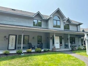 Een tweelaags huis met een veranda, een voordeur en een kleine voortuin.