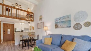 A living room with a blue sofa, wooden dining table, and a kitchen in the background. - Ephraim’s Pearl (Unit 203) | Balcony Views, Walk to Waterfront and Downtown Charm (Ephraim)