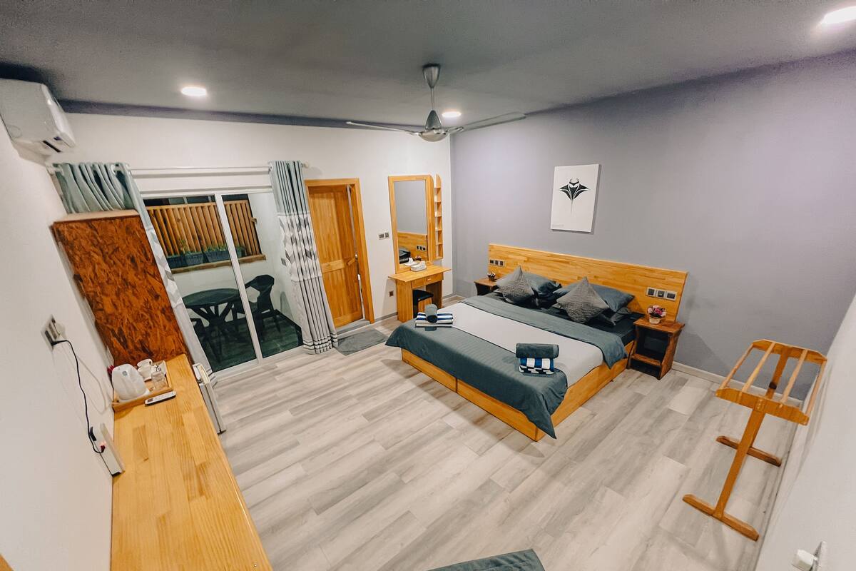 A modern bedroom with a wooden bed, bedside tables, a desk, and a chair.