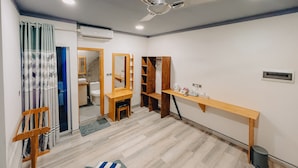 A modern room with a ceiling fan, wooden furniture, a small desk, and a mirror.
