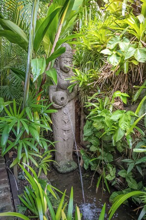 A stone statue in a lush garden with a water feature. - Sanctuary Studio (The Pocket)
