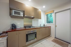 A modern kitchen with stainless steel appliances, wooden countertops, and beige cabinetry. - Sanctuary Studio (The Pocket)