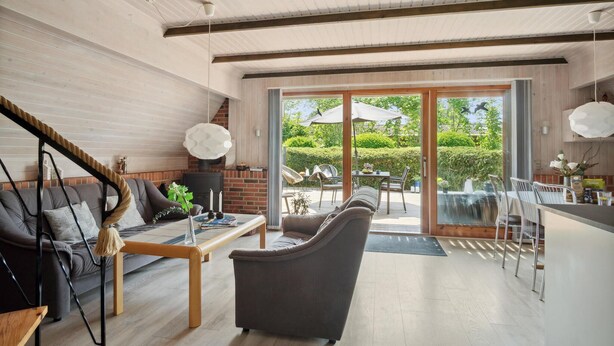 Una sala de estar moderna con chimenea, un comedor y un amplio ventanal corredera que da a un patio exterior.