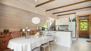 Una cocina moderna con armarios blancos, una isla central y un comedor con mesa blanca y sillas de metal.