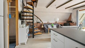 Una cocina moderna con una isla central, estufa integrada y una escalera de madera.