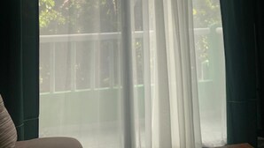 A room with a large window, a view of a balcony with a railing, and a wooden table. - Remarkable Studio in jungle of Chemuyil, Tulum (Chemuyil)
