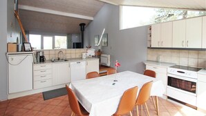 Una cocina compacta con comedor, refrigerador, estufa y lavamanos.