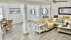 En moderne stue med en modulsofa, et sofabord og et spiseområde med bord og stole.