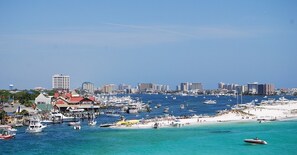 A coastal cityscape with a marina filled with boats, a sandy beach, and a city skyline in the background. - 5-bedroom vacation home just few minutes to Destin Beach (Fort Walton Beach)