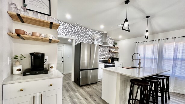 Una cocina moderna con una isla central, electrodomésticos de acero inoxidable y una barra con taburetes.