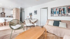 A modern living room with a wooden coffee table, two wicker chairs, a beige sofa, and a painting of lighthouses on the wall. - 3 bedroom nice home in Les Portes-en-Ré (Les Portes-en-Ré)