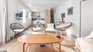 A modern living room with a wooden coffee table, wicker chairs, and a kitchen in the background. - 3 bedroom nice home in Les Portes-en-Ré (Les Portes-en-Ré)
