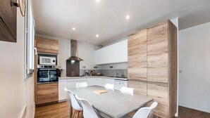 A modern kitchen with wooden cabinets, a built-in oven, and a dining area with a table and chairs. - 3 bedroom nice home in Les Portes-en-Ré (Les Portes-en-Ré)
