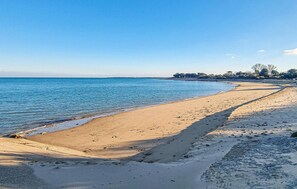 Une plage de sable fin, sous un ciel bleu azur et une mer calme.