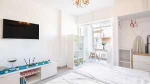 A bright, modern bedroom with a large bed, a TV mounted on the wall, a desk, and a wardrobe. - RENTAS Benalmádena Beach Studio (Benalmadena)