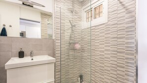 A modern bathroom with a glass-enclosed shower, a white sink, and a mirror above it. - RENTAS Benalmádena Beach Studio (Benalmadena)