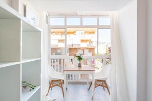 A balcony with a table and chairs, a vase with flowers, and a view of a residential building. - RENTHAS Studio in Benalmádena (Benalmadena)