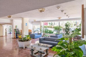 A spacious lobby with seating, a reception desk, and potted plants.