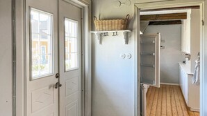 A hallway with a white door, a window, and a shelf with a basket. - Nice home in Agunnaryd with kitchen (Agunnaryd)