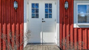 A red wooden door with two windows and two wall-mounted lanterns. - Nice home in Agunnaryd with kitchen (Agunnaryd)