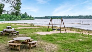 A lakeside picnic area with wooden benches and a swing set. - Nice home in Agunnaryd with kitchen (Agunnaryd)