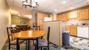 Une cuisine moderne avec des meubles en bois, une table à manger avec des chaises, un réfrigérateur et un lave-vaisselle.