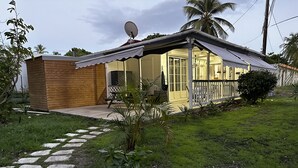 Uma casa com fachada de madeira, varanda com guarda-corpo branco e antena parabólica.
