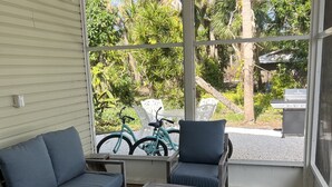 A covered patio with a ceiling fan, a sofa, two chairs, a small table, and a patterned rug. - Beach house - 3 min walk to beach! (Englewood)