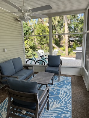 Relax in this serene sunroom with a garden view, featuring a sofa, armchairs, and a coffee table.