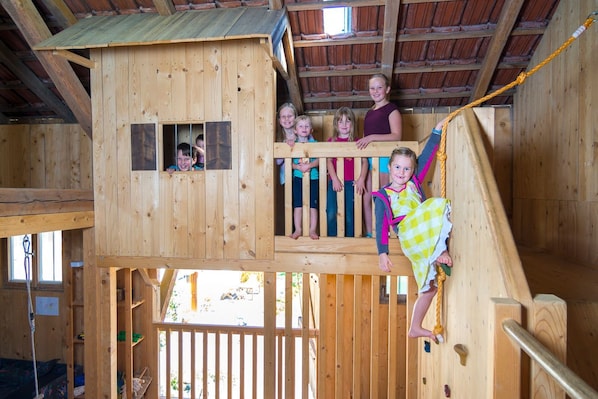 A wooden playhouse with a slide and a rope ladder.