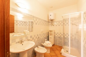 A bathroom with a sink, bidet, toilet, and a glass-enclosed shower.