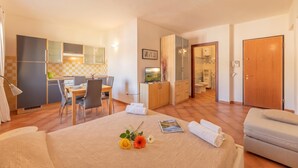 Habitació d'hotel amb llit, escriptori, cadira, petita cuina i bany.