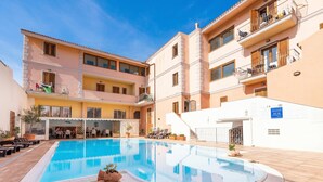 Zona de piscina amb terrassa solària, seients exteriors i una zona de menjador coberta.