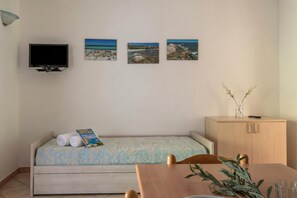 A room with a bed, a TV, and three framed pictures on the wall.