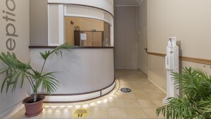 A reception area with a curved counter, potted plants, and a sign indicating social distancing measures. - Le Fontane Bilocale 3P 4Km From The Sea, Villasimius, Italy (Villasimius)